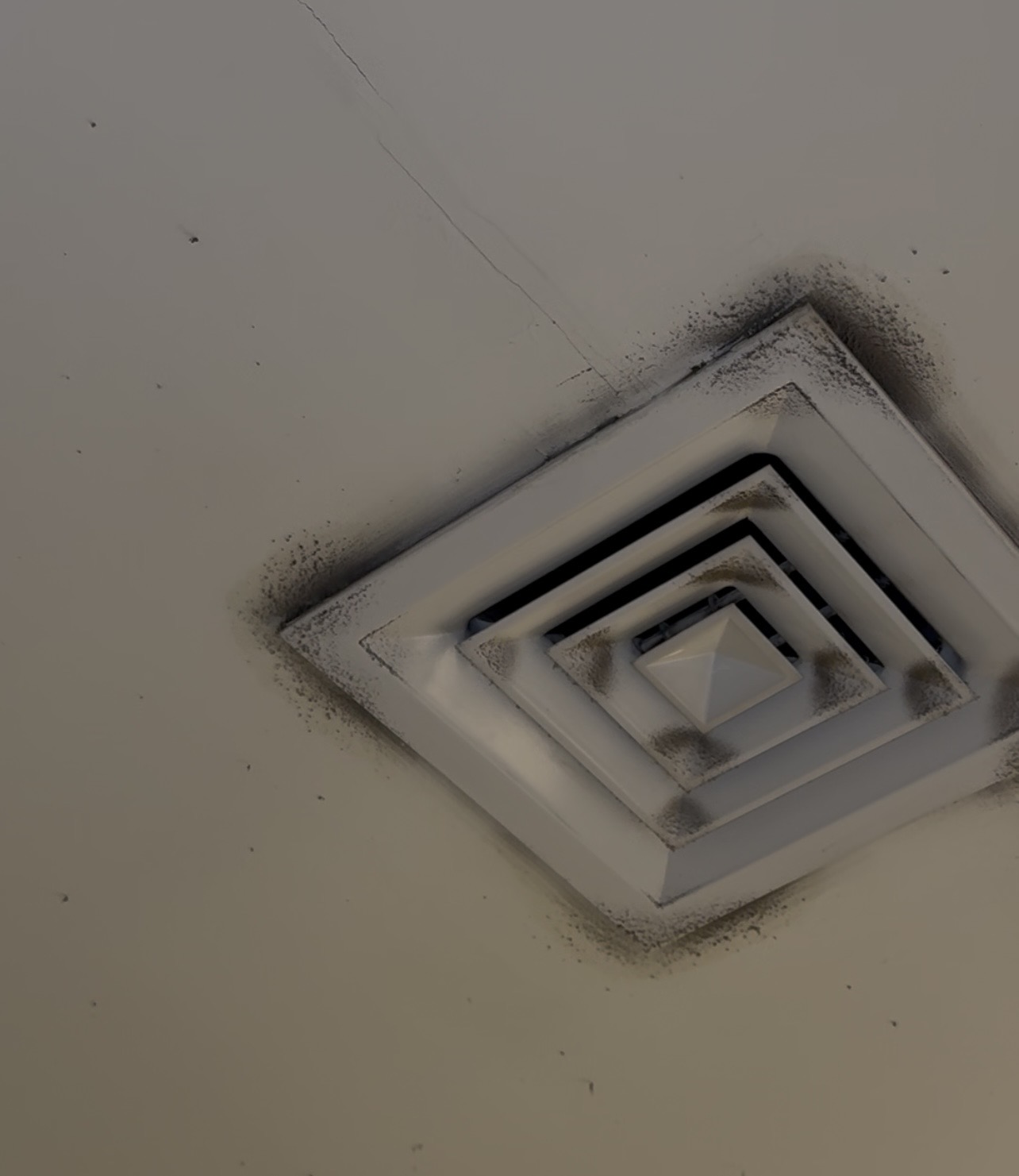 HVAC ceiling diffuser showing visible contamination around the air outlet