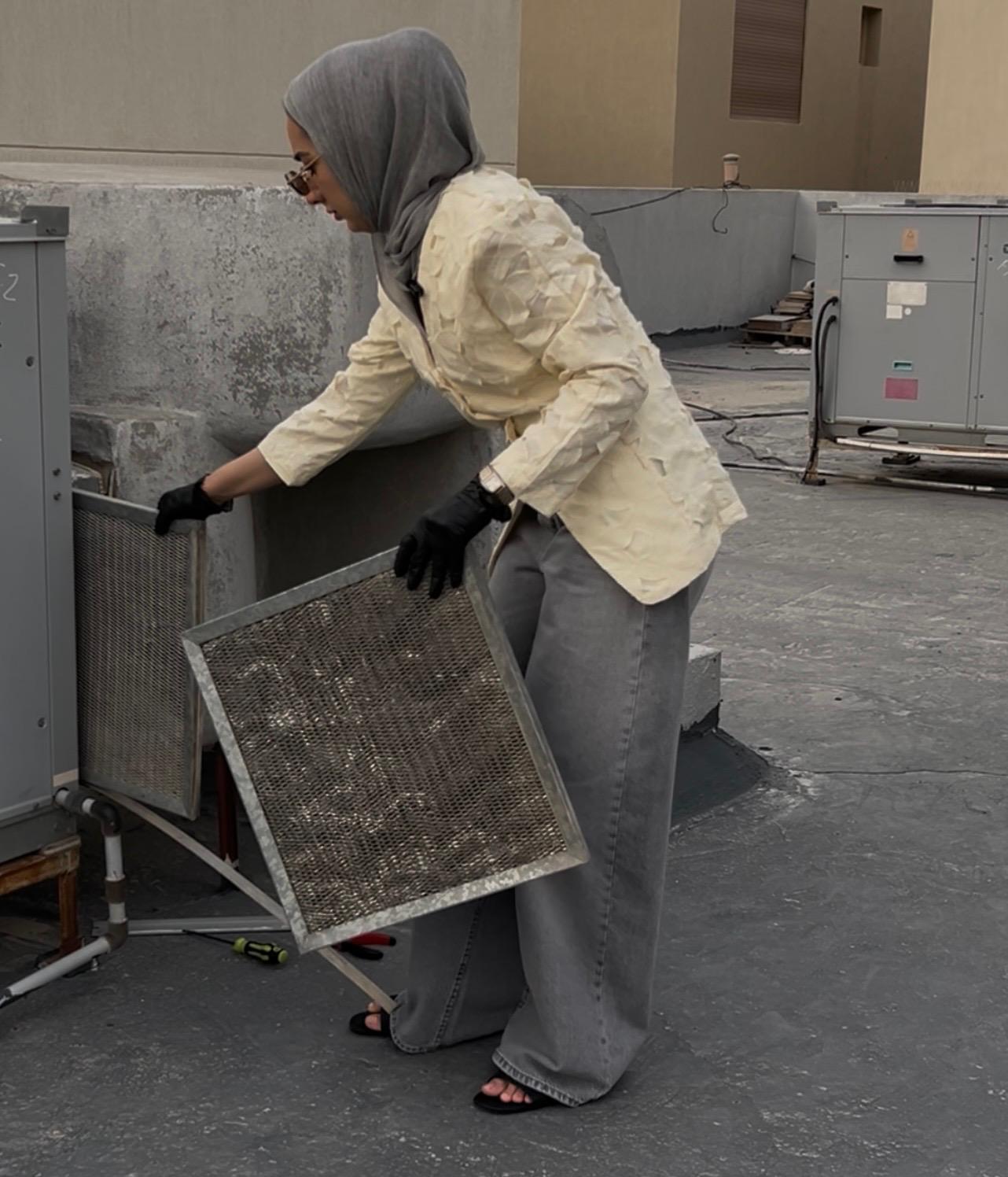 Shaikha conducting a rooftop HVAC filtration inspection