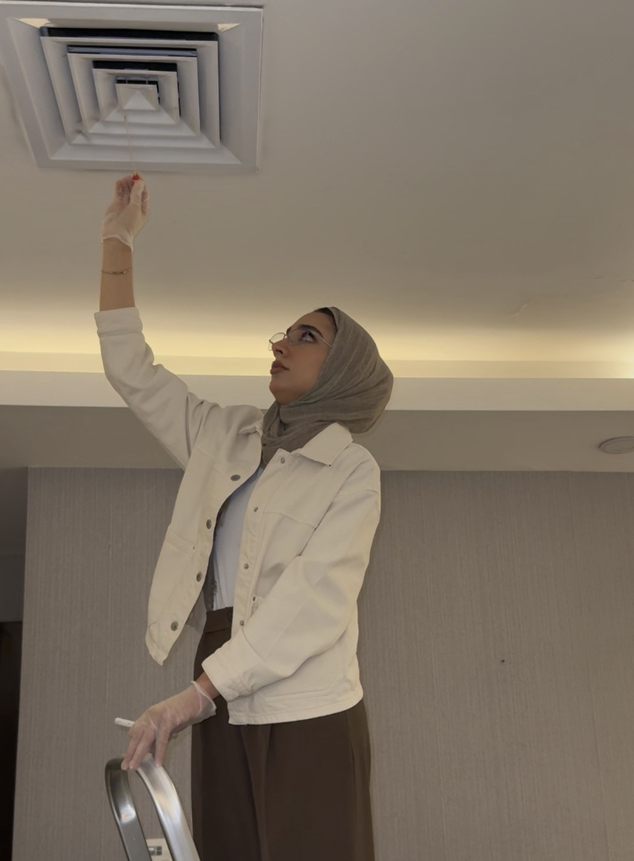 Shaikha inspecting an HVAC air diffuser